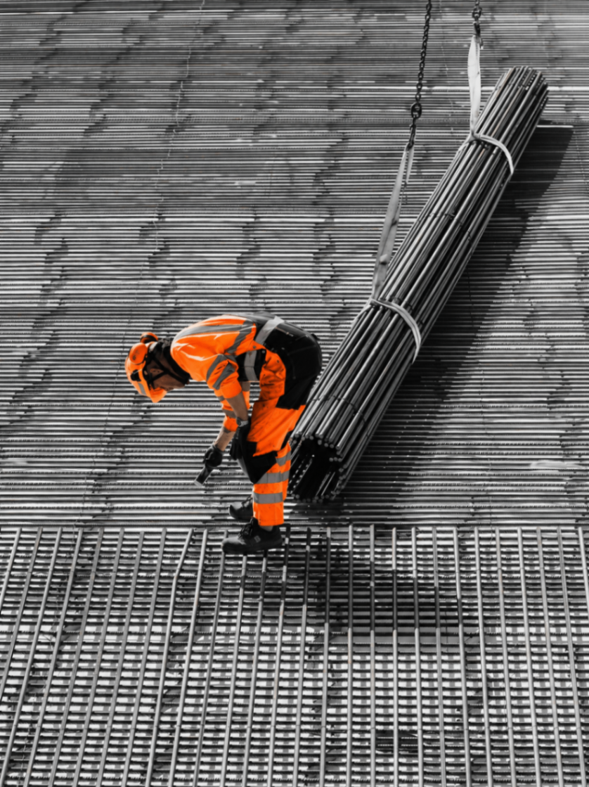 Worker adjusting rebar mesh with crane load